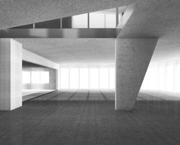 Großer, offener Innenraum mit Betonwänden und -stützen, hohen Decken und breiten Fensterfronten, die viel Tageslicht hereinlassen. Moderne, minimalistische Architektur mit klaren Linien. – Klicken zum Vergrößern